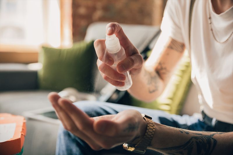 Hand wird mit Desinfektionsspray desinfiziert.