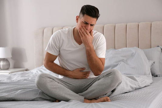Mann mit Norovirus sitzt krank auf dem Bett.